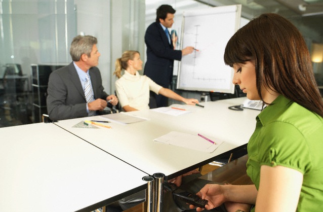 Young Businesswoman Using Cell Phone During Meeting